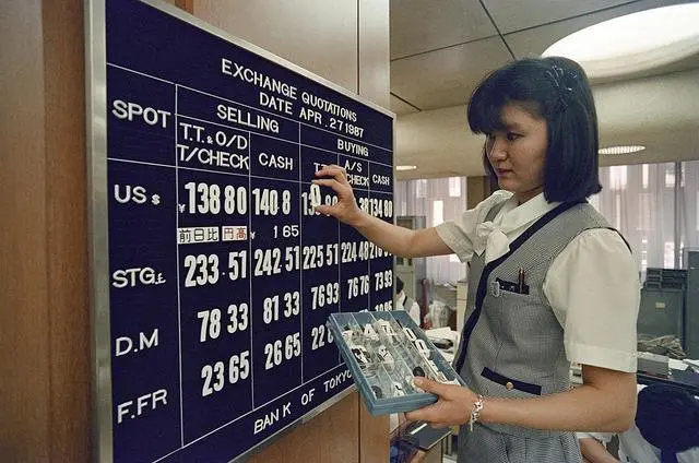 當(dāng)?shù)貢r(shí)間1987年4月27日，日本東京，證券交易所，一名銀行職員在公告板上展示新的匯率，此時(shí)美元跌至戰(zhàn)后最低水平。視覺中國(guó)