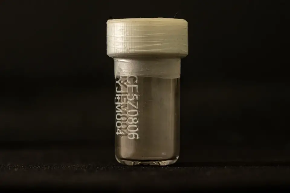 托尼·喬利夫/英國廣播公司新聞 一個小的透明小瓶，白色塑料瓶蓋，瓶蓋周圍有膠帶。它在黑色背景下被照亮。正面有一個編碼。底部內(nèi)部有一層灰塵。