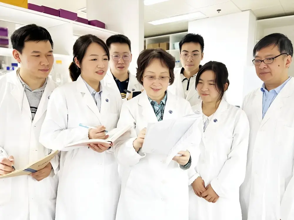 雷群英教授（前排居中）與團隊在實驗室討論。復旦大學 供圖