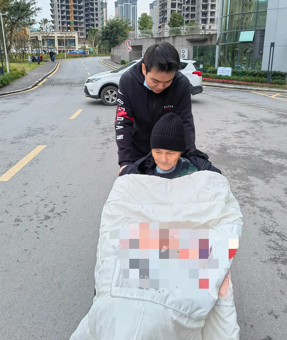 患病后的吴德明（戴帽者）靠坐轮椅出行。